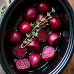 A bowl of balsamic roasted beets garnished with thyme, cooked in a crockpot for a healthy, flavorful side dish.