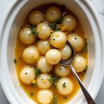 Wholesome lemon thyme pearl onions recipe cooked in a crockpot, showcasing a vibrant glaze and fresh herbs.